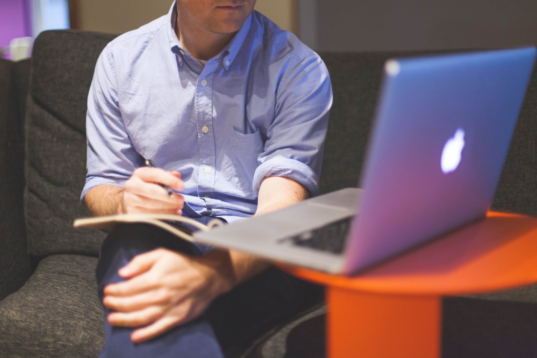 man sitting on couch in front of macbook