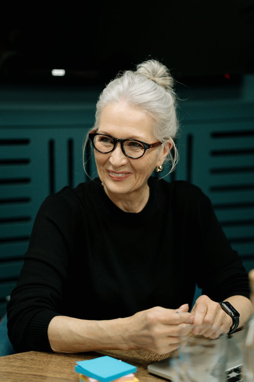 smiling woman in black long sleeve shirt wearing eyeglasses